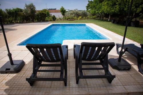two chairs and a table next to a swimming pool at Passo do Lobo - Turismo Rural in Moura