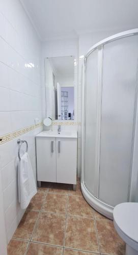 a white bathroom with a shower and a sink at La Voreta in Villajoyosa