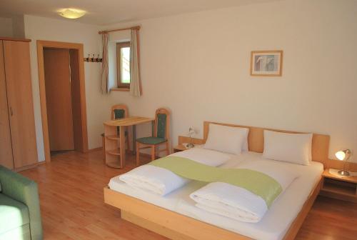 a bedroom with a bed and a table with a chair at Berggasthof Bärnstatt in Scheffau am Wilden Kaiser