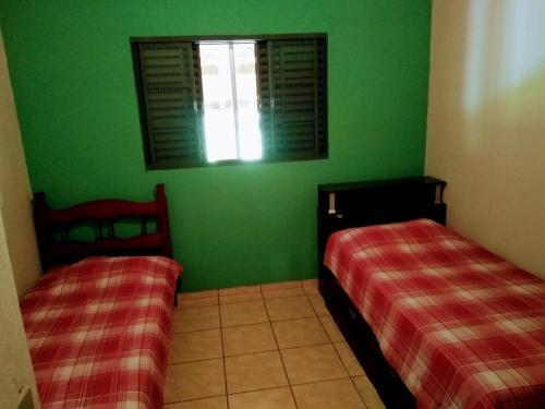 two beds in a room with green walls and a window at Casa de sitio em Brotas in Brotas