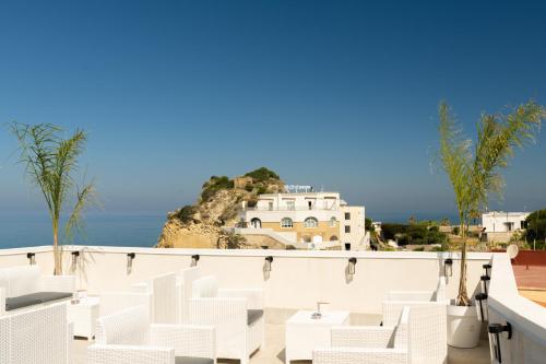 a balcony with white chairs and a view of the ocean at Naro Suites and Rooms in Bacoli