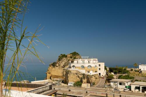 a building on a cliff next to the ocean at Naro Suites and Rooms in Bacoli