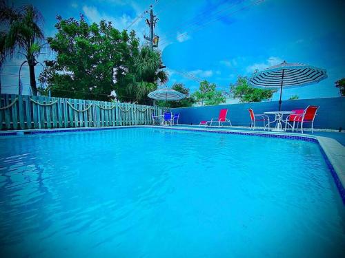 duży niebieski basen z krzesłami i parasolem w obiekcie Secret Serenity! Roomy! Pool! 5 min from Beach! w mieście Deerfield Beach