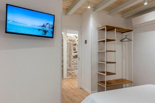 a bedroom with a tv on the wall and a book shelf at In centro da Viola - Eco Design Rooms in Olbia