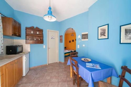 a kitchen and dining room with a blue wall at Santorious Flower Covered Apartment in Megalochori