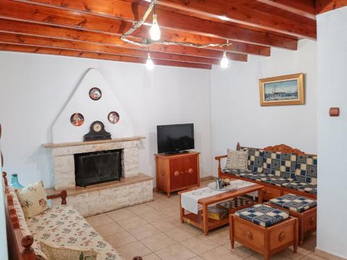 a living room with a fireplace and a tv at Mikros Paradisos Pelion in Áyios Vlásios