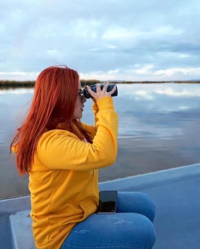 a woman sitting on a boat taking a picture of the water at UROS KAY PACHA Lodge in Puno
