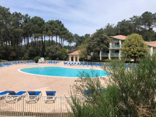 Una piscina con sillas azules y un resort. en Jolie petite maison à Vieux Boucau avec piscine chauffée - Domaine du Golf de Pinsolle, en Soustons