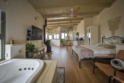 a bedroom with a bed and a bath tub at צימר חלון לרקפות zimer Window for primroses עם ג'קוזי לנוף in Tal Shaẖar