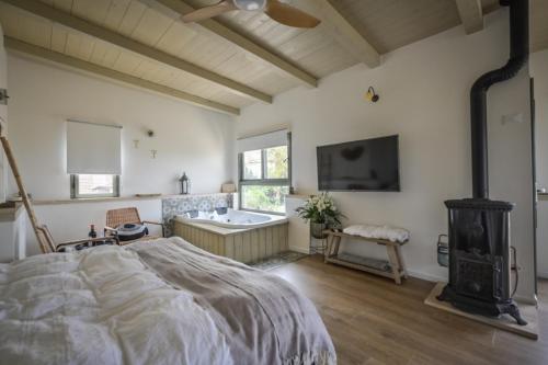 a bedroom with a bed and a tub and a tv at צימר חלון לרקפות zimer Window for primroses עם ג'קוזי לנוף in Tal Shaẖar