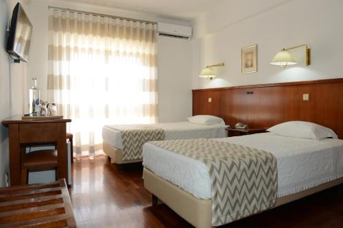 a hotel room with two beds and a window at Estalagem Sequeira in São Brás de Alportel