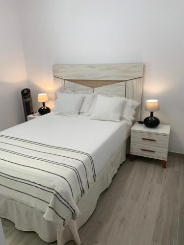 プエルト・デル・カルメンにあるCasa Johnのベッドルーム(白い大型ベッド、ランプ2つ付)