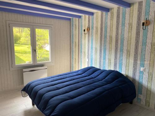 una camera con un letto blu e una finestra di LE GITE DU LYNX a Cernon