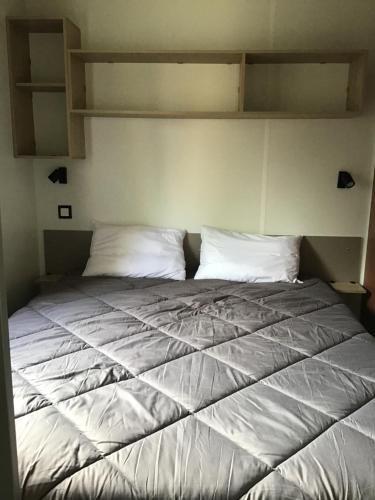 un lit avec des draps blancs et des oreillers dans une chambre dans l'établissement Mobil home neuf, à Biscarrosse