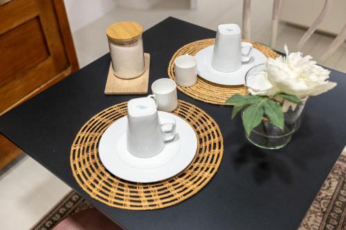 a table with two plates and cups and a vase of flowers at Piran Holiday Apartments in the city center in Piran