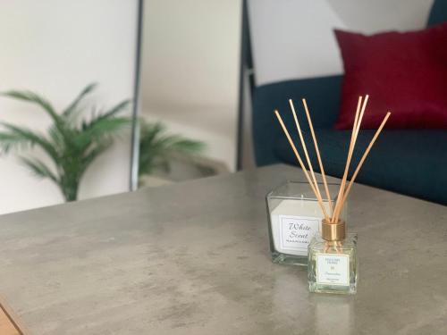 um frasco de uma vela sobre uma mesa com paus de bambu em Minimalist Apartment em Sófia