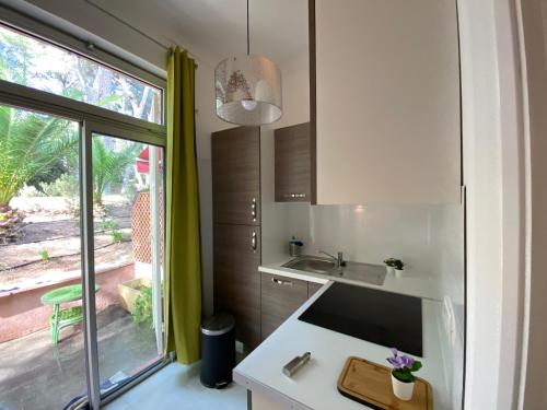 une petite cuisine avec un évier et une fenêtre dans l'établissement L Annexe 50m de la plage, à Bandol