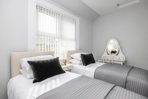 2 Betten in einem weißen Zimmer mit Spiegel in der Unterkunft Cosy town centre cottage in Peebles