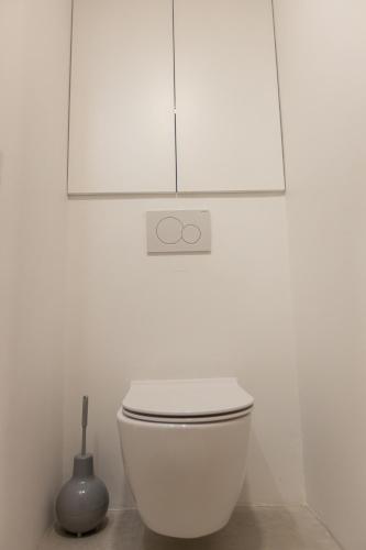 a white bathroom with a toilet and a white cabinet at Piran Holiday Apartments in the city center in Piran