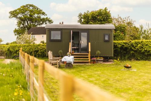 a green tiny house in a yard with a fence at Mulsford Cottage in Malpas