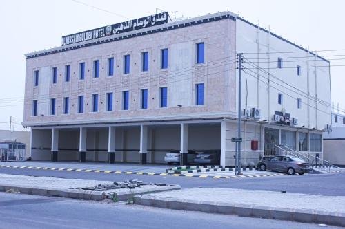 un grande edificio in mattoni con macchine parcheggiate di fronte di فندق الوسام الذهبي a Al Ḩanākīyah