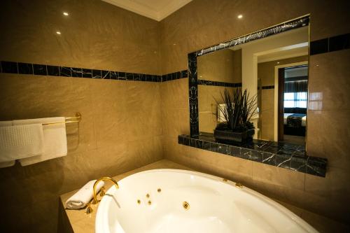 a bathroom with a tub and a large mirror at Gallery Apartments in Warrnambool