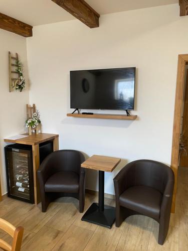 a living room with two chairs and a table and a tv at Rodinný penzion Kohoutek in Hovorany
