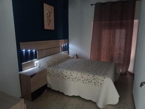 een slaapkamer met een bed met een houten hoofdeinde bij Casa Rosarito in Aracena