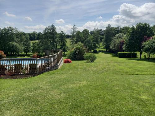 a yard with a wooden fence and green grass at La Gasteboisiere with swimming pool and games room in Le Mesnil-Adelée