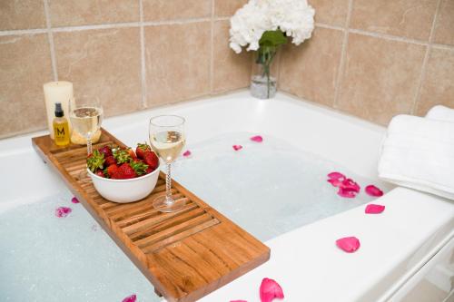 a bathtub with a bowl of strawberries and glasses of wine at Luxe Quiet Townhouse w/Parking/Pool/By Dollywood in Pigeon Forge