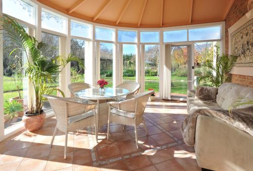 a conservatory with a table and chairs and a couch at Lakeside Cottage Luxury B&B in Mount Dandenong
