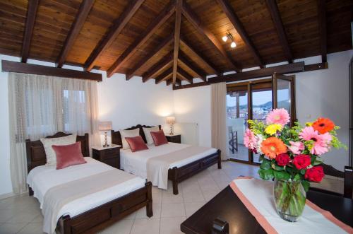 a bedroom with two beds and a vase of flowers at Afrodite Hotel Apartments in Myrina