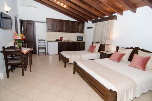 a bedroom with two beds and a table and a kitchen at Afrodite Hotel Apartments in Myrina