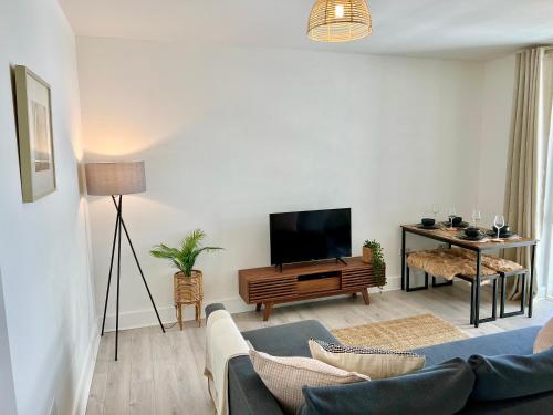 2 Bedroom Serviced Apartment with Free Parking, Wifi & Netflix, Basingstoke في باسينغستوك: غرفة معيشة مع أريكة وتلفزيون بشاشة مسطحة