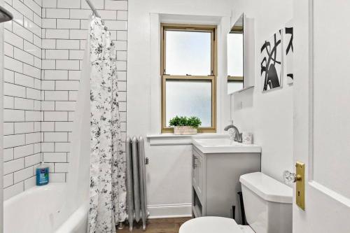 a white bathroom with a tub and a toilet and a sink at Stylish 2BR Apt in Vibrant Avondale near Shops - Roscoe 1W in Chicago