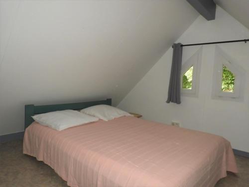a bedroom with a bed with two pillows and two windows at Village 17 gites, Piscine, Restaurant , 2 gites avec SPA, 3km de Conques in Conques