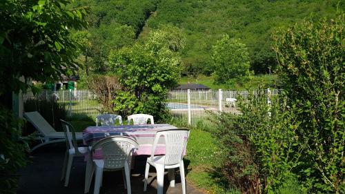 a table and chairs in a yard with a fence at Village 17 gites, Piscine, Restaurant , 2 gites avec SPA, 3km de Conques in Conques