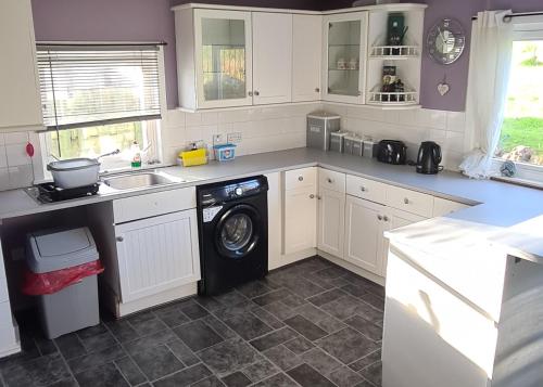 a kitchen with a washing machine and a sink at Spacious rural cottage outside Campbeltown in Campbeltown