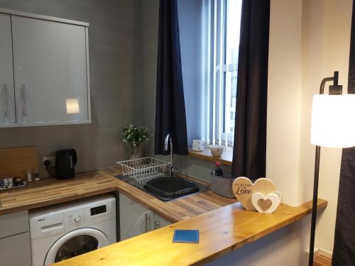 a kitchen with a sink and a washing machine at One bedroom flat, very close to Town center. in Oban