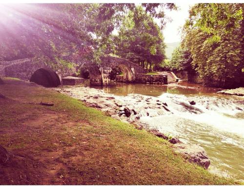 a river with a bridge next to a grass field at GÎTE AZKENDANTZA 2a6 PERS AVEC CARAVANE INSOLITE in Ascain