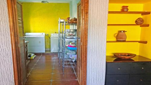 a kitchen with yellow walls and a kitchen with a shelf at Villa Meli 2 in Jocotepec