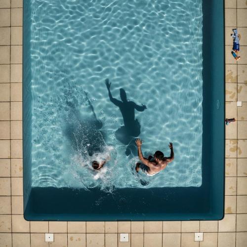 2 personnes nagent dans une piscine dans l'établissement Le Chevrefeuille chambres d'hotes et gîtes de charme, à Meyrals