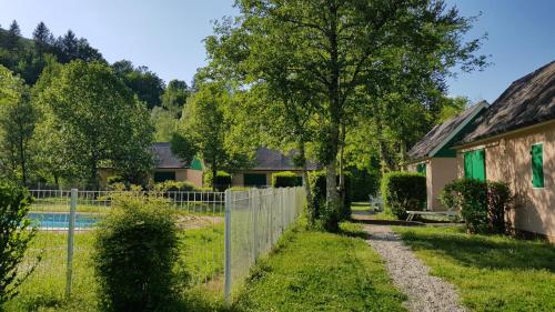 a fence in front of a house and a yard at Village 17 gites, Piscine, Restaurant , 2 gites avec SPA, 3km de Conques in Conques