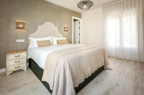 a bedroom with a large white bed and a window at El Rincón de Silvia. in Ayamonte