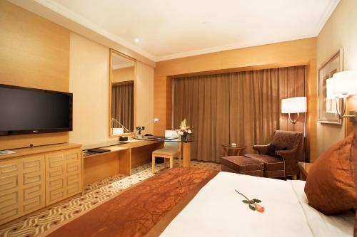 a hotel room with a bed and a flat screen tv at Hotel Nikko Wuxi in Wuxi