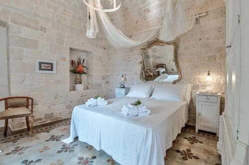 a bedroom with a white bed and a mirror at Borgo Altobello in Cisternino