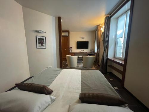 a bedroom with a bed with two chairs and a television at Véritable Suite d'Hotel! in Orange