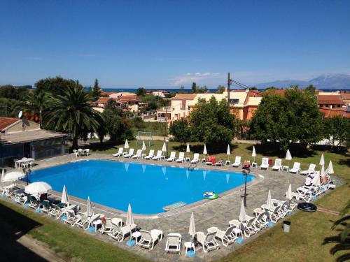 a large swimming pool with lounge chairs and umbrellas at Tzilios Studios in Acharavi