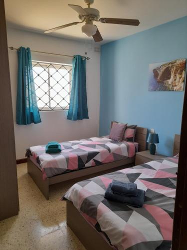 een slaapkamer met 2 bedden en een plafondventilator bij Sunshine Holiday Apartment 4 Next to the Sea in St Paul's Bay