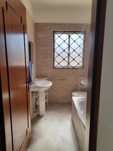 een badkamer met een wastafel, een bad en een raam bij Sunshine Holiday Apartment 4 Next to the Sea in St Paul's Bay